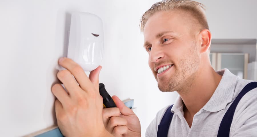 Man installing a motion detector on a wall